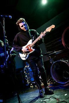 a man standing in front of a microphone and guitar