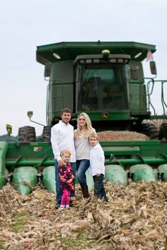 a man, woman and child standing in front of a large green farm equipment truck