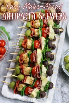 an appetizer with olives, tomatoes and meat on skewers is ready to be eaten