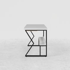 a white table sitting on top of a cement floor next to a black metal frame