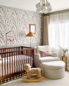 a baby's room with a crib, rocking chair and wallpapered walls