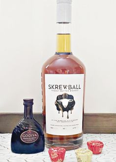 a bottle of skreww ball rum next to three shot glasses