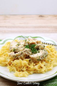 a white plate topped with pasta covered in sauce and chicken meat on top of it