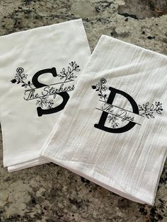 two white towels with the letter s and d printed on them sitting next to each other