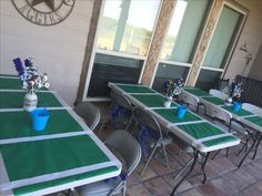 tables and chairs are set up outside with blue vases on each table, along with flowers in the middle