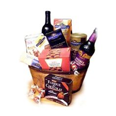 a basket filled with lots of different types of food and wine next to two bottles of wine