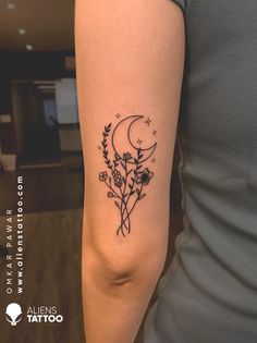 a woman's arm with a tattoo on it that has flowers and the moon