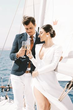 a man and woman standing on the deck of a boat holding wine glasses in their hands