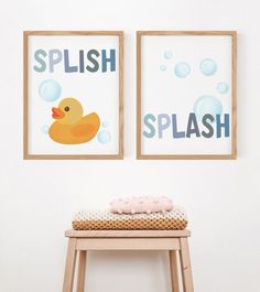 two framed pictures hang on the wall next to a stool with a baby's name and rubber ducky