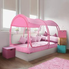 a pink canopy bed sitting in a bedroom next to a window