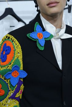 a man in a black jacket with crocheted flowers on it