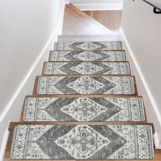 a set of stairs leading up to an upstairs hallway with carpeted treads and rugs