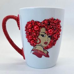 a white coffee cup decorated with red beads and a woman's face on it