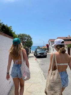 two women walking down the street with bags on their backs and one carrying a purse