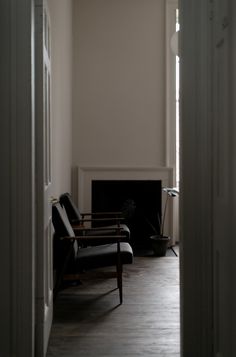 an empty room with two chairs and a fireplace