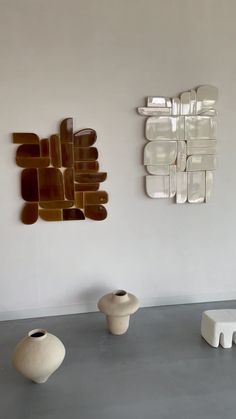 three white vases are sitting on the floor in front of a wall with art