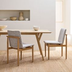 two chairs sitting at a table with bowls on the shelves behind them in a white room