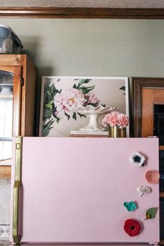 a pink refrigerator with magnets and flowers on it