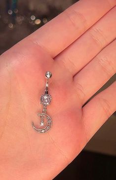 a person's hand holding a diamond and pearled crescent belly ring in their left hand