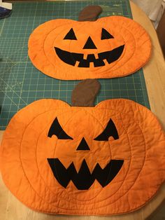 two quilted pumpkins sitting on top of a cutting board