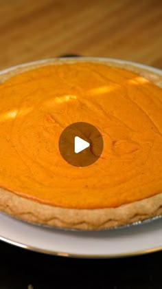 a pumpkin pie on a plate with a video play button in the top right corner