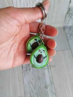 a hand holding a keychain with a green and black animal on it