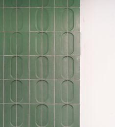 a white toilet sitting in front of a green tiled wall with circles and bars on it