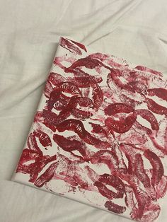 a red and white painting on top of a white sheet with watercolor pencils