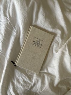 an open book sitting on top of a white bed sheet covered in wrinkle