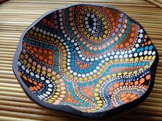 a colorful bowl sitting on top of a wooden table next to a bamboo place mat