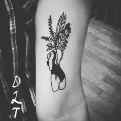 a black and white photo of a plant tattoo on the left arm, which has a woman's hand holding a potted plant