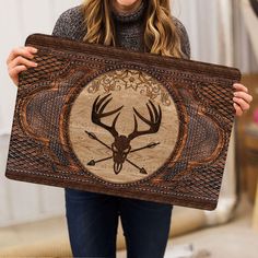 a woman holding up a wooden plaque with an image of a deer's head