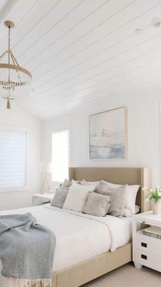 a bedroom with a bed, dresser and chandelier hanging from it's ceiling