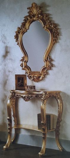 an ornate gold console table with a mirror on top and a book shelf below it