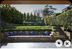 a couch sitting on top of a stone patio next to a lush green park filled with trees