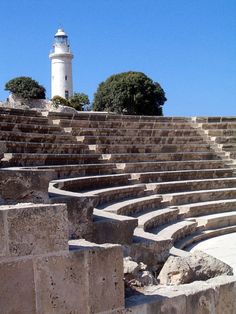 an outdoor seating area with stone steps and a lighthouse in the background