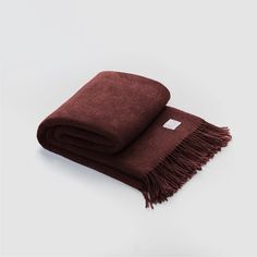 a brown blanket folded on top of a white surface with a tag in the middle