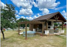 a hot tub sitting in the middle of a yard next to a tree and covered patio