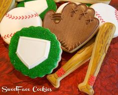 decorated cookies in the shape of baseballs and mitts on a red tablecloth