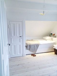 an open door leading to a bedroom with white walls and wood flooring on the bottom level