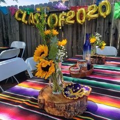 a table with sunflowers and other decorations on it in front of a fence