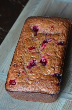 a loaf of fruit bread sitting on top of a wooden cutting board