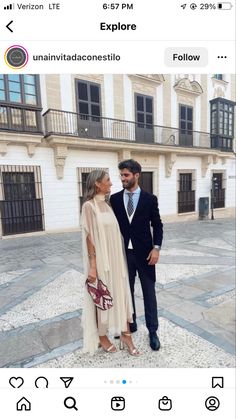 a man and woman standing next to each other in front of a building with windows