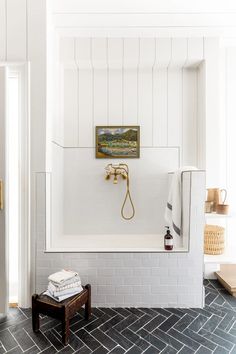 a bathroom with white walls and tile flooring has a painting hanging on the wall