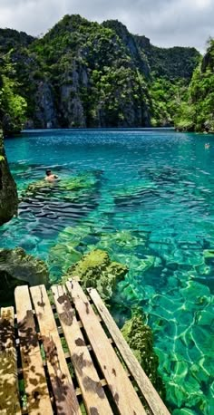 the water is crystal blue and clear with some people swimming in it at the bottom