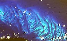 an aerial view of the ocean with blue and white waves on it's surface