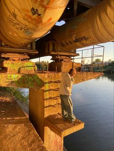 a man standing on top of a bridge next to a river under an overpass