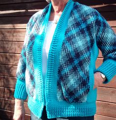 an older woman standing in front of a wooden fence wearing a blue sweater and jeans