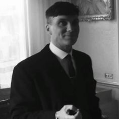 a black and white photo of a man in a suit holding a piece of food