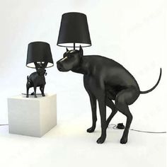 a black dog standing next to a lamp on top of a white block with a black lampshade